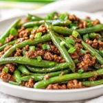 Delicious Garlic Green Beans With Ground Beef Served On A White Plate Garnished With Scallions And Garlic