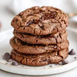 Stack Of Gluten-Free Double Chocolate Cookies On A White Plate With Melted Chocolate Chips And A Dusting Of Cocoa Powder