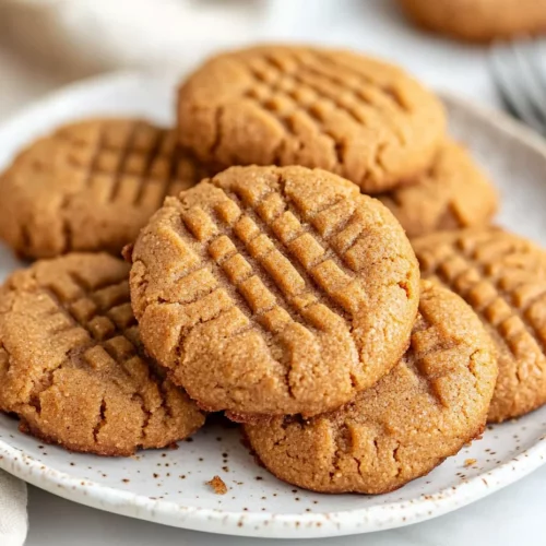 Low-Carb Almond Butter Cookies With A Hint Of Cinnamon 2 Soft Low-Carb Almond Butter Cookies With A Crisscross Pattern And Cinnamon Dusting On A White Plate With A Beige Napkin