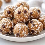 Peanut Butter Energy Balls On A White Plate Garnished With Shredded Coconut And Chocolate Chips