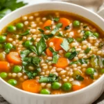 Bowl Of Vegetable Barley Soup Garnished With Parsley And Basil, Showcasing Colorful Vegetables And Hearty Broth