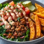 Delicious Burger Bowl With Special Sauce, Topped With Fresh Veggies And Crispy Sweet Potato Fries On The Side.
