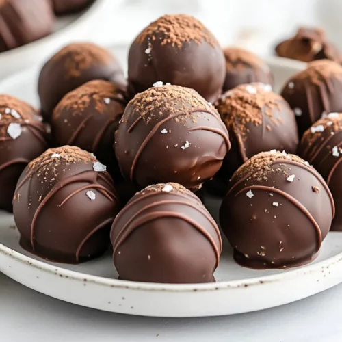 Chocolate-Covered Date Truffles: The Perfect Healthy Snack 2 Delicious Chocolate-Covered Date Truffles On A White Plate, Garnished With Flaky Sea Salt And Cocoa Powder