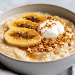 Bowl Of Cinnamon Porridge With Baked Bananas Topped With Yogurt And Seeds On A Light Background