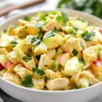 Curry Chicken Salad In A White Bowl Topped With Fresh Cilantro And Diced Apples