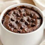 Delicious Easy Mug Brownie Served In A White Mug Garnished With Mini Chocolate Chips On A Wooden Table