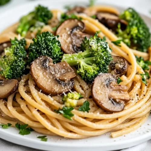 Delicious Easy Mushroom Broccoli Pasta Served On A White Plate, Garnished With Parsley And Vibrant Broccoli Florets