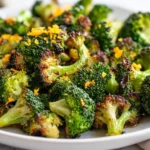Delicious Garlic Roasted Broccoli With Orange On A White Plate, Garnished With Fresh Orange Zest.