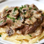 Delicious Gluten-Free Beef Stroganoff Over Gluten-Free Pasta, Garnished With Parsley On A White Plate