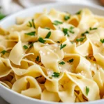 Plate Of Gluten-Free Egg Noodles Garnished With Parsley And Olive Oil, Showcasing Silky Texture On A White Dish