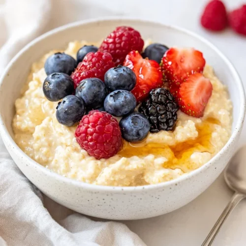 Best Gluten-Free Porridge Recipe For A Healthy Breakfast 2 Bowl Of Gluten-Free Porridge Topped With Peanut Butter, Maple Syrup, And Fresh Berries On A White Plate