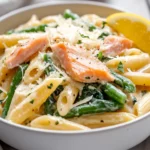 Bowl Of Gluten-Free Salmon Pasta Garnished With Smoked Salmon, Spinach, And Lemon On A White Background.