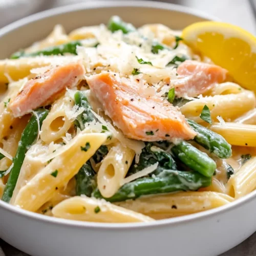 Bowl Of Gluten-Free Salmon Pasta Garnished With Smoked Salmon, Spinach, And Lemon On A White Background.
