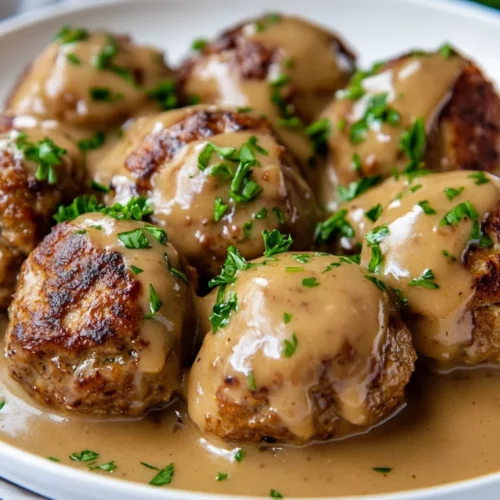 Gluten Free Swedish Meatballs In Creamy Gravy On A White Plate, Garnished With Parsley And Invitingly Warm