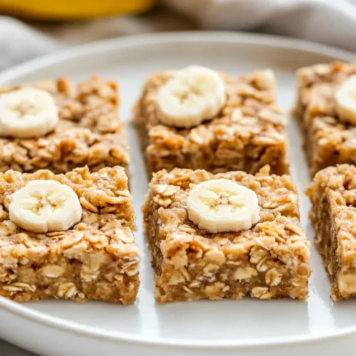 Healthy Banana Oatmeal Bars: The Perfect Nutrient-Packed Snack 2 Freshly Baked Healthy Banana Oatmeal Bars On A White Plate Garnished With Walnuts And Banana Slices