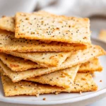 Crispy Homemade Almond Flour Crackers Stacked On A White Plate With A Sprinkle Of Seasoning And A Cozy Kitchen Towel