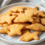 A Plate Of Crispy Homemade Goldfish Crackers With A Light Salt Sprinkle, Arranged Invitingly On A White Plate.