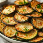 Crispy How To Make Zucchini Chips Served On A White Plate, Garnished With Fresh Parsley And Accompanied By Ranch Dip
