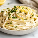 Creamy Lemon Ricotta Spaghettoni In A White Bowl Garnished With Scallions And Cracked Pepper