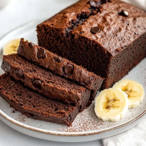 Moist Chocolate Banana Bread Recipe: Healthy, Oil-Free, And Easy 2 Moist Chocolate Banana Bread Slices On A White Plate Garnished With Cocoa Powder And Banana Slices