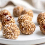 No-Bake Peanut Butter Jelly Bites On A White Plate, Topped With Coconut Flakes And Chia Seeds, Showcasing Their Chewy Texture.