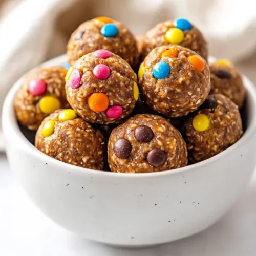 Close-Up Of No Bake Protein Balls Vegan In A White Bowl, Topped With Colorful Chocolate Pieces And Bright Lighting
