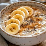 Bowl Of Overnight Oats With Brown Sugar Topped With Banana Slices And Chia Seeds, Served On A Rustic White Bowl.