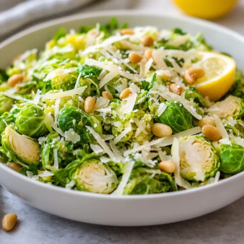 Parmesan Brussels Sprouts Salad: A Healthy And Flavorful Favorite 2 Parmesan Brussels Sprouts Salad In A White Bowl Garnished With Lemon Zest And Toasted Pine Nuts