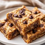 Delicious Peanut Butter Banana Bars On A White Plate, Topped With Melted Chocolate Chips And Oats