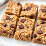 Peanut Butter Granola Bars On A White Plate, Drizzled With Honey And Garnished With Crushed Nuts