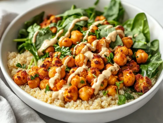 Bowl Of Roasted Chickpea Curry Bowl Topped With Spinach And Tahini-Lime Dressing, Served On A White Dish