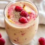 Thick Stress Relief Smoothie In A Clear Glass, Topped With Hemp Seeds And Fresh Raspberries On A Wooden Table