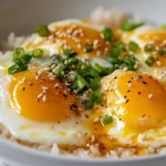 Bowl Of Tamago Kake Gohan With Creamy Eggs And Garnished With Scallions And Sesame Seeds