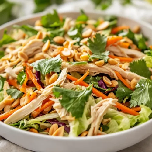 Colorful Vietnamese Chicken Salad In A White Bowl, Topped With Fresh Herbs And Roasted Peanuts, On A Neutral Background.