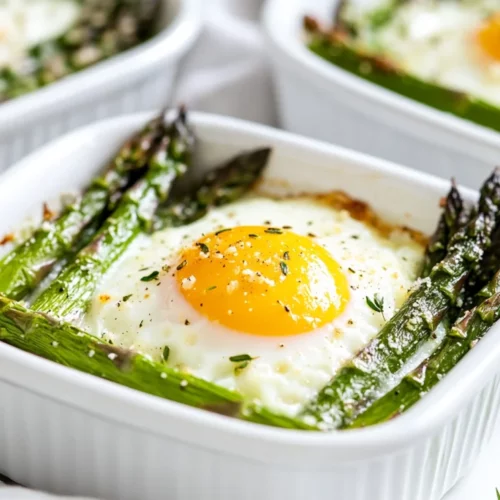 Baked Asparagus With Eggs Served In White Dishes, Topped With Parmesan Cheese And Fresh Herbs