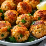 Plated Baked Chicken Meatballs Garnished With Parsley And Lemon Wedges On A White Plate