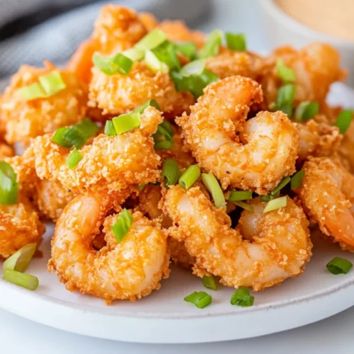 Crispy Bang Bang Shrimp Air Fryer On A White Plate Garnished With Sliced Green Onions And Shredded Romaine