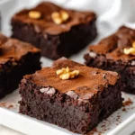 Fudgy Black Bean Brownies On A White Plate Dusted With Cocoa Powder And Topped With Walnuts