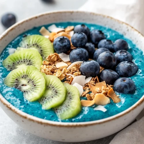 Blue Smoothie Bowl: A Healthy, Protein-Packed Breakfast Idea 2 Blue Smoothie Bowl Topped With Kiwi, Blueberries, And Coconut Chips, Served In A White Bowl