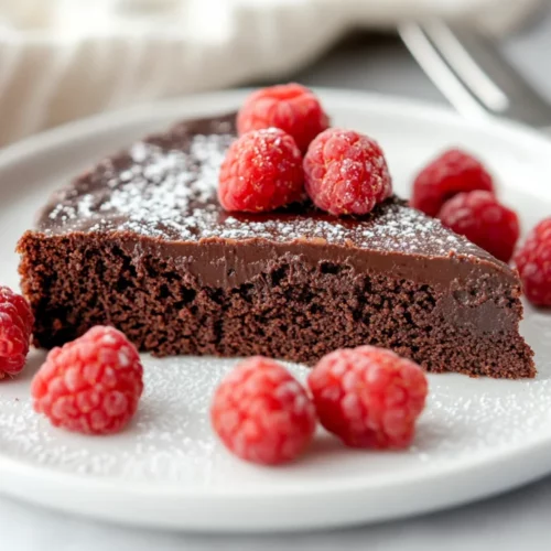 The Best Flourless Chocolate Cake Recipe – Gluten-Free &Amp; Easy! 2 Delicious Flourless Chocolate Cake On A White Plate, Topped With Fresh Raspberries And Powdered Sugar