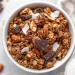 Bowl Of Grain-Free Banana Bread Granola With Chewy Clusters Of Nuts And Dark Chocolate On A Neutral Table