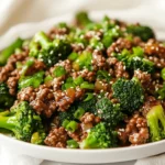 Delicious Ground Beef And Broccoli Stir Fry On A White Plate, Garnished With Sesame Seeds And Green Onions.