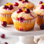 Healthy Cranberry Orange Muffins On A White Plate Garnished With Orange Zest, Showcasing Their Golden Tops And Juicy Cranberries.
