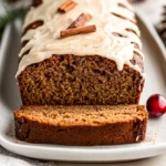 Healthy Gingerbread Loaf Drizzled With Maple Cream Cheese Frosting On A White Plate, Garnished With Cranberries