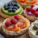 Colorful Healthy Rice Cake Snacks Topped With Almond Butter, Berries, Avocado, And Smoked Salmon On A Rustic Wooden Board