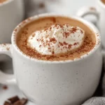 Creamy High Protein Hot Chocolate Topped With Coconut Whipped Cream In A White Mug On A Kitchen Towel