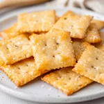 Crispy Homemade Cheese Crackers Arranged On A White Plate With A Sprinkle Of Sea Salt