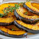 How To Roast Acorn Squash Slices On A White Plate Garnished With Fresh Thyme And Crushed Red Pepper