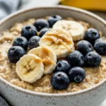 Bowl Of Instant Pot Steel Cut Oats Topped With Fresh Blueberries And Banana Slices, Drizzled With Almond Butter.