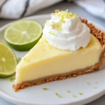 Slice Of Key Lime Pie On A White Plate Garnished With Whipped Cream And Lime Zest